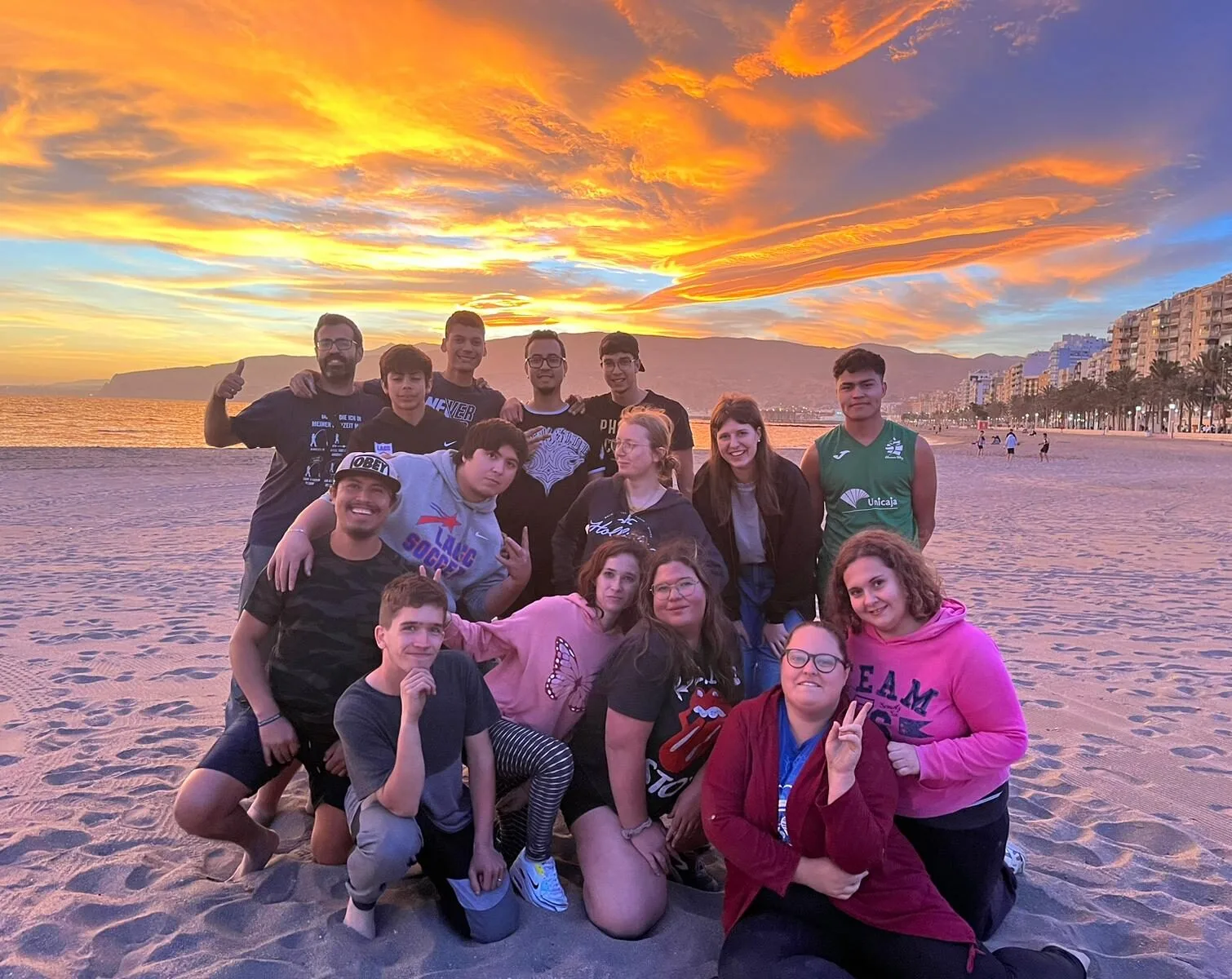 Grupo de jóvenes posando en la playa al atardecer