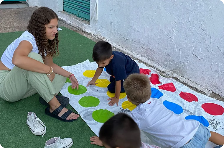Una monitora juega al Twister con tres niños sobre el césped