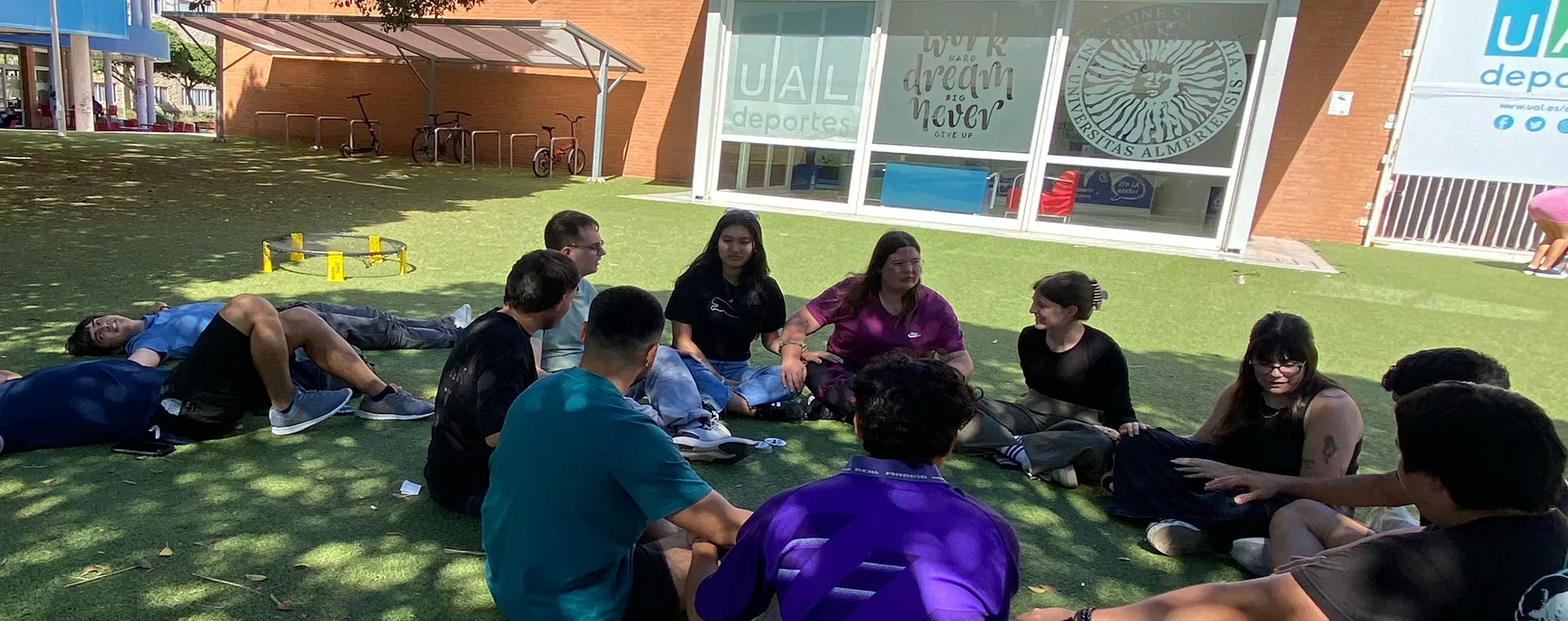 Estudiantes sentados en el césped del campus universitario