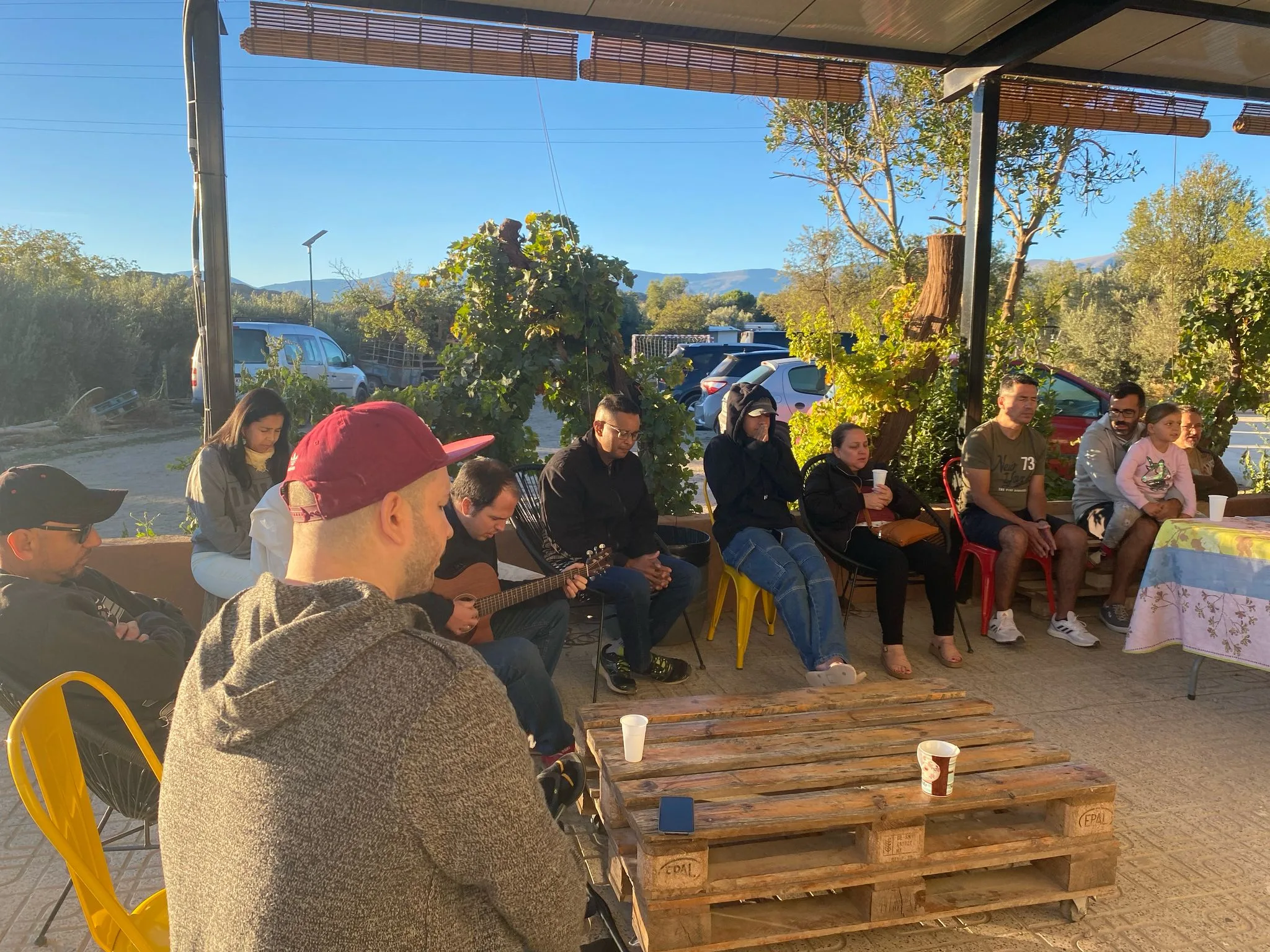 Servidores sentados al aire libre alrededor de un guitarrista